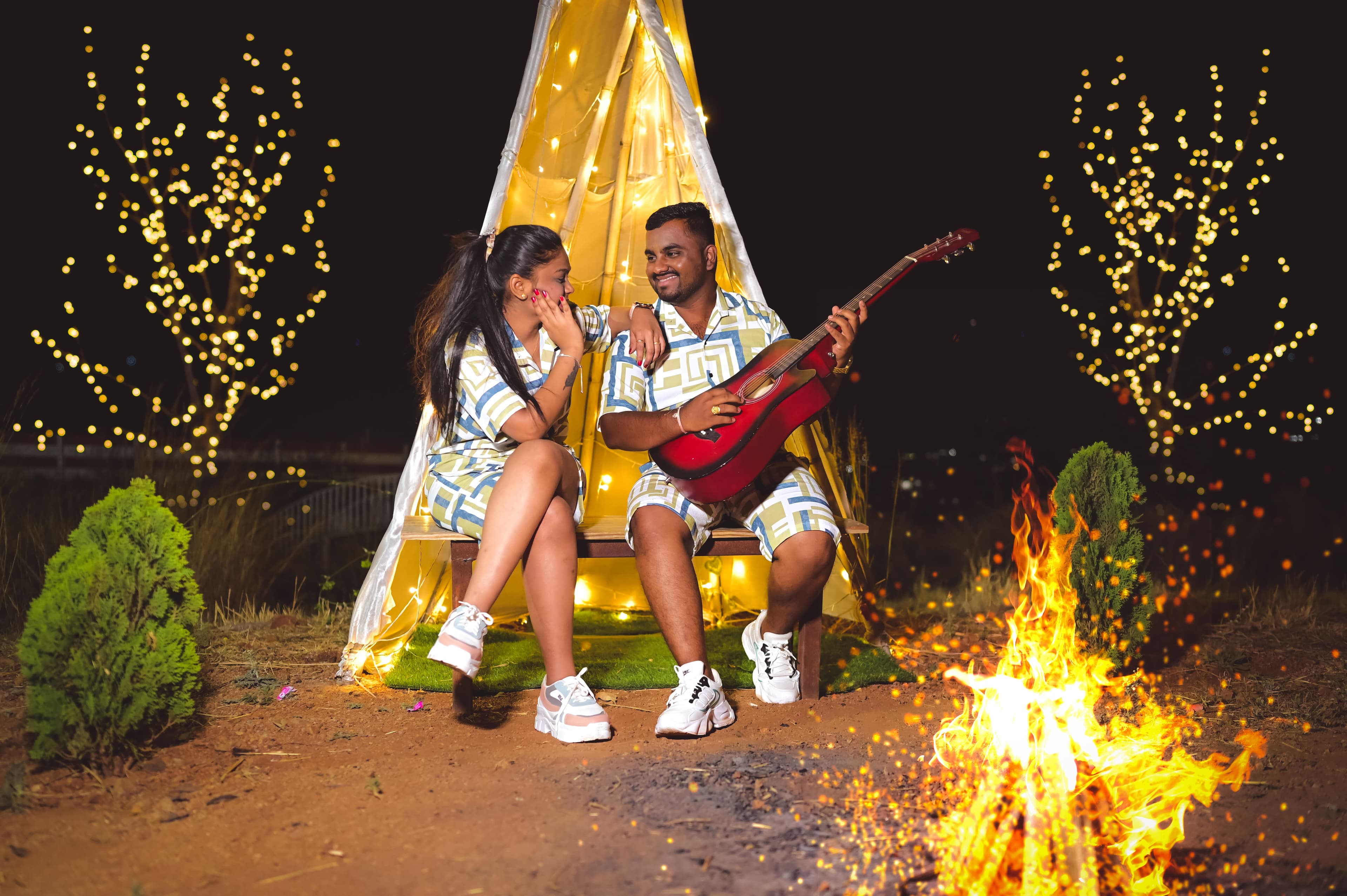 Couple by a campfire with fairy lights and a guitar, night pre-wedding shoot